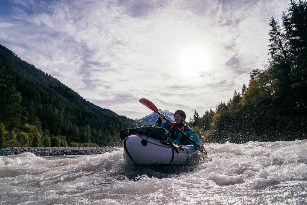 Packraft-Kurs: Der Schlüssel zu sicherem und selbstbewusstem Packrafting 2 Participants of the packraft course on the Lech navigate through crystal-clear waters, surrounded by the stunning Austrian Alps