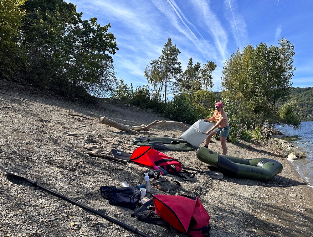 Aufpumpen eines Packrafts am Seeufer während eines Packrafting-Abenteuers in der deutschen Eifel